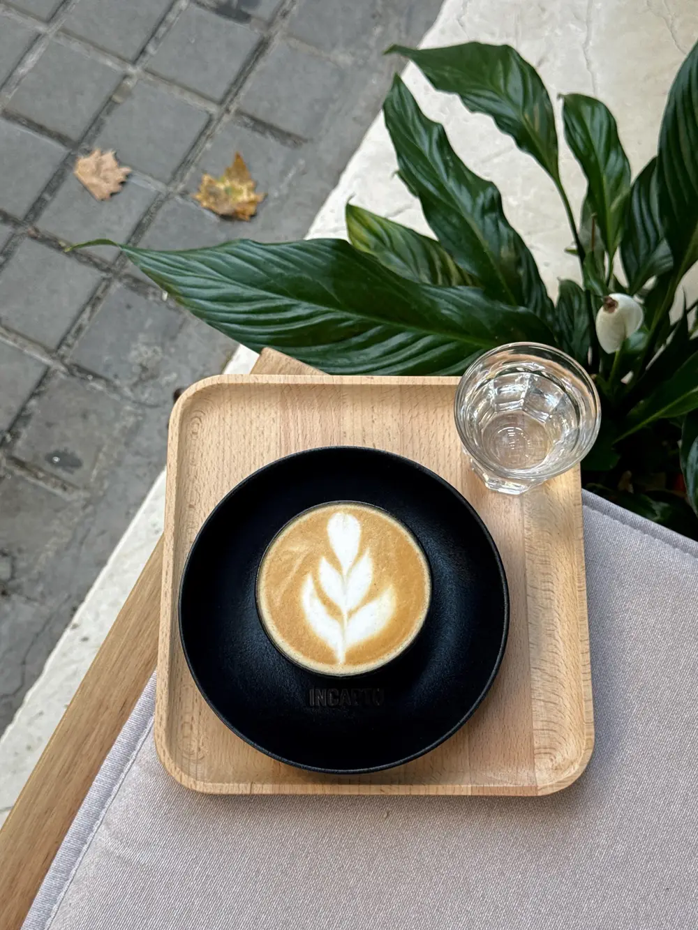 A latte with leaf art on an Incapto saucer, on a wooden tray