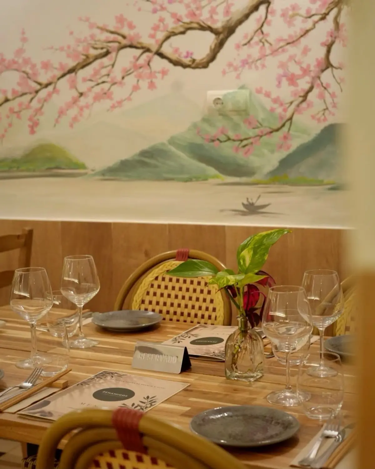 A table set under the cherry blossom mural, with a Reservado sign