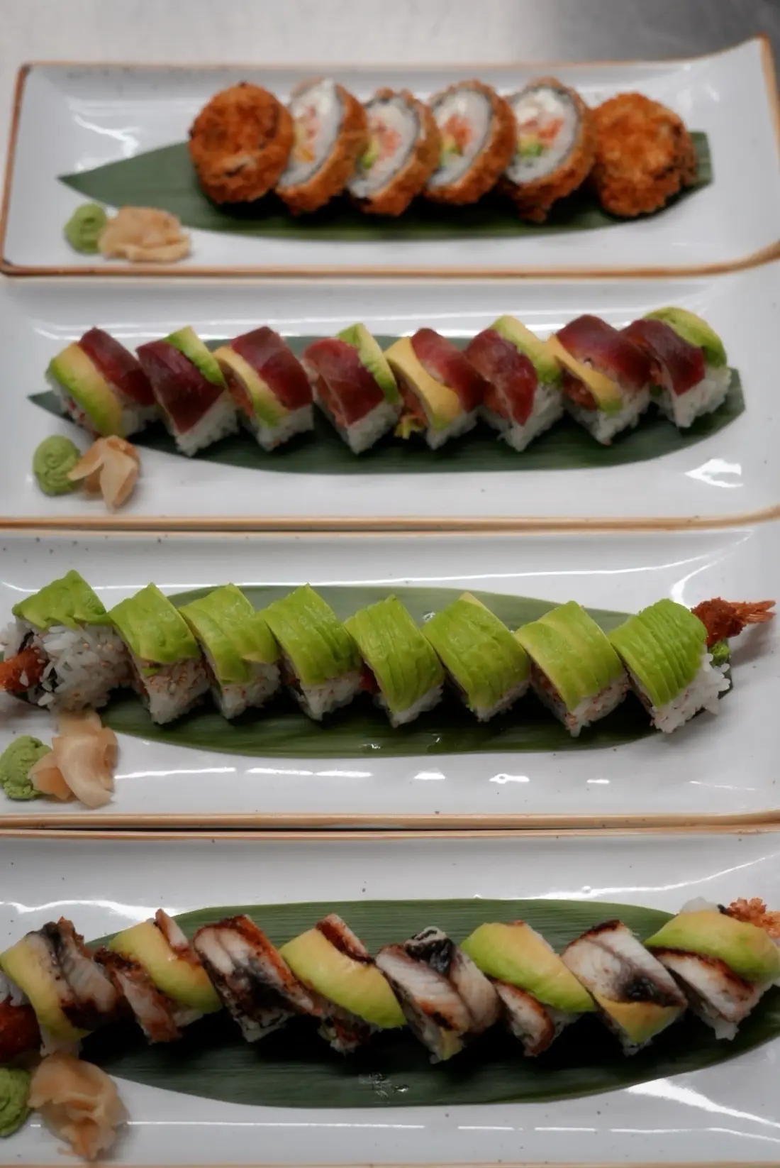 Four plates of sushi rolls lined up on the pass in our kitchen